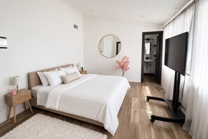 Een slaapkamer met een bed, nachtkastjes, een televisie en een spiegel.