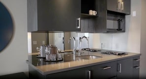 Een moderne keuken met een groot eiland, roestvrijstalen apparatuur en donkere kastjes.