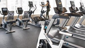 A gym with stationary bikes and treadmills, large windows, and a city view. - Dominion Grand Suites Toronto (Toronto)