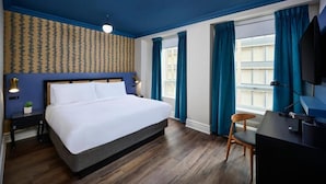 A hotel room with a large bed, a desk, a chair, a TV, and a window with curtains. - Market Square Boutique Hotel (Toronto)