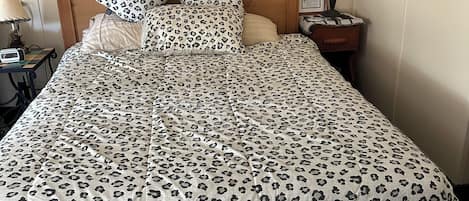 Una habitación de hotel con una cama, una mesita de noche, una lámpara y un cuadro enmarcado.