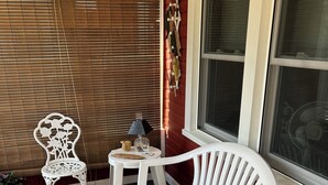 A room with a white plastic chair, a small round table, and a wicker basket containing a magazine.