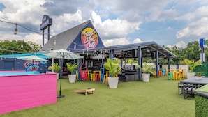 An outdoor seating area with a covered patio, artificial grass, and colorful chairs. - HOST/EL Boutique Shared Rooms  (Houston)