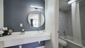 A bathroom with a white sink, a mirror, a toilet, and a shower area. - HOST/EL Boutique Shared Rooms  (Houston)