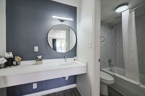 Un bany amb un lavabo blanc, un mirall, un vàter i una zona de dutxa.