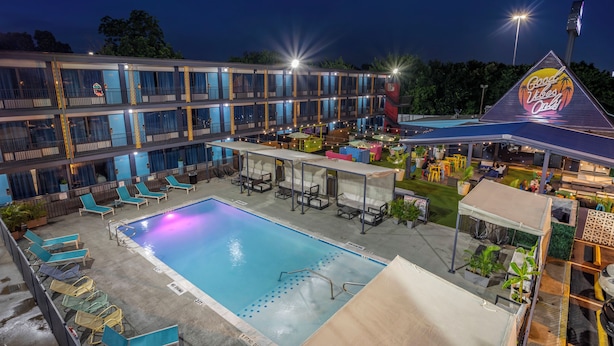A hotel with a swimming pool, outdoor seating, and a building with multiple balconies. - HOST/EL Boutique Shared Rooms  (Houston)
