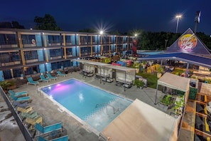 A hotel with a swimming pool, outdoor seating, and a building with multiple balconies. - HOST/EL Boutique Shared Rooms  (Houston)