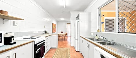 Eine moderne Küche mit weißen Schränken, einem Herd, einem Backofen und einem großen Fenster mit einem Metallgitter.