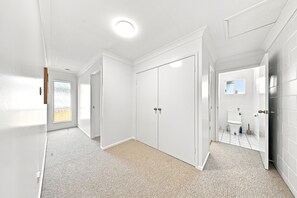 En gang der fører til et soveværelse med et skab, et badeværelse med toilet og en brusezone.