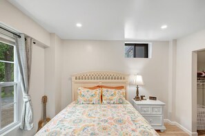 A bedroom with a bed, a nightstand, a lamp, a guitar, and a window with curtains. - Backyard Breeze: Modern 1BR with Walk-In Shower Near BNA (Nashville)