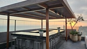 Eine Dachterrasse mit Bar, Sitzgelegenheiten und Topfpflanzen.