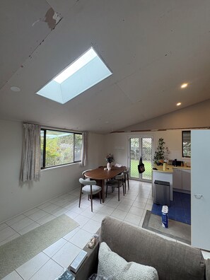 A modern living room with a dining table, sofa, and kitchen area with a small island. - Coastal short term rental (Golden Beach)