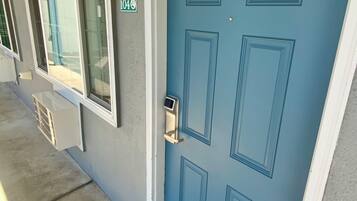 Una puerta azul con cerradura electrónica, una ventana con vista a una piscina y un letrero con el número '404' en la pared.