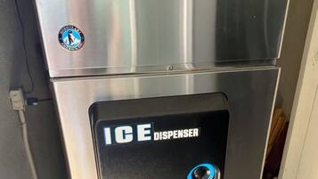 A stainless steel Hoshizaki ice dispenser with a push button and a logo on the top.