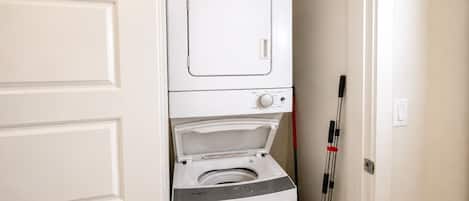 A laundry room with stacked appliances, including a dryer and a washing machine.