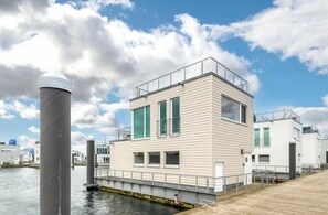 A modern waterfront building with a flat roof, large windows, and a dock extending into the water. - Holiday Home Baltic Home Olpenitz (Kappeln)