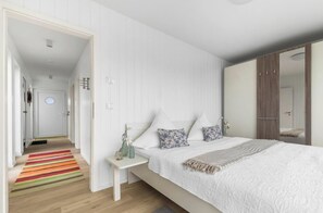 Ein Schlafzimmer mit einem Bett, einem Nachttisch und einem farbenfrohen Streifen Teppich.