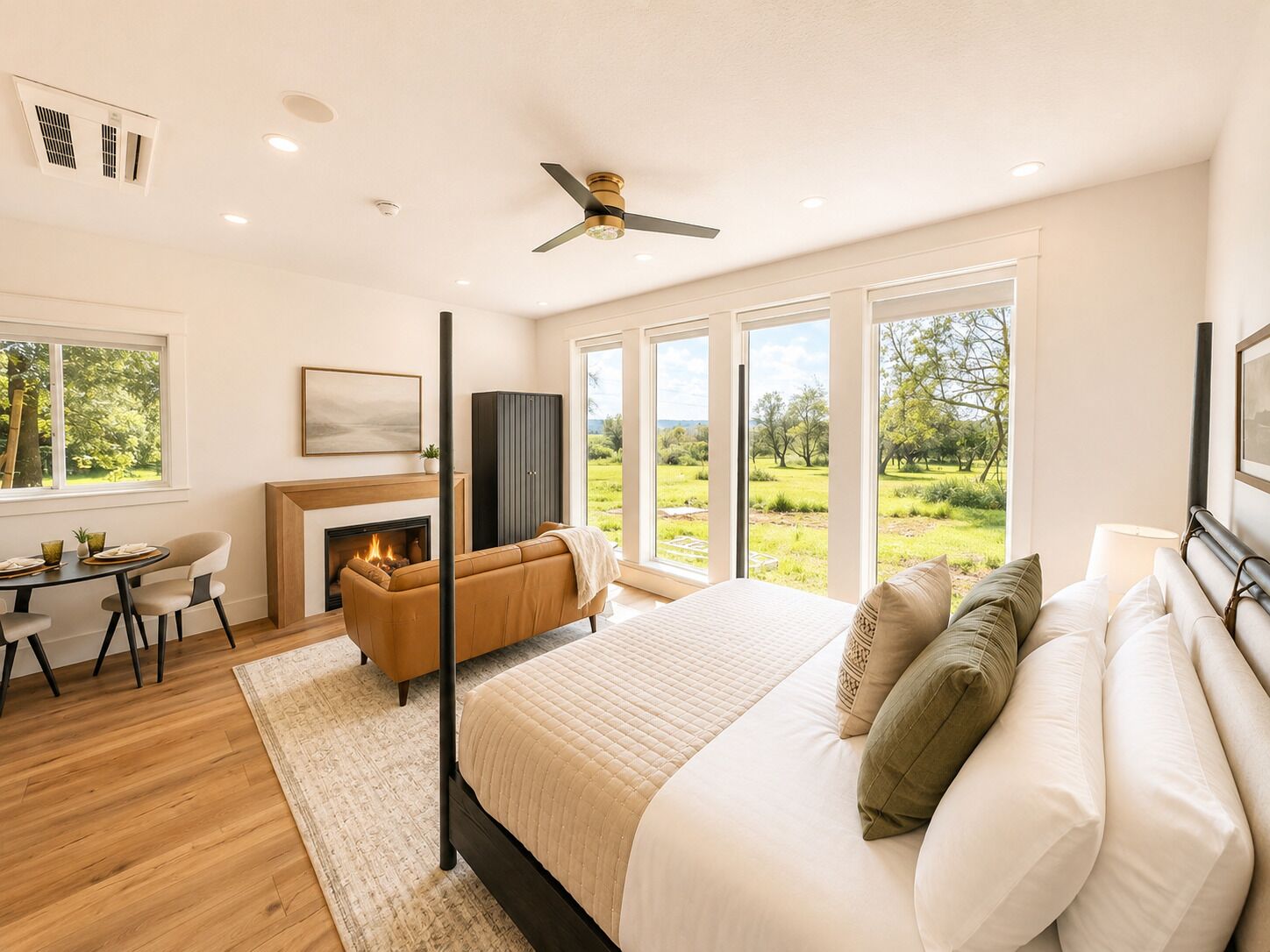 Quarto com cama grande, lareira, sofá e vista para uma paisagem verde.