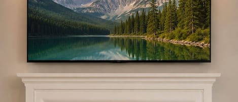 A fireplace with a framed landscape painting above it.