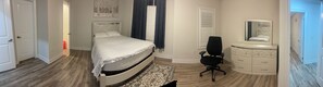 Ein Schlafzimmer mit Bett, Schminktisch, Stuhl und Spiegel.