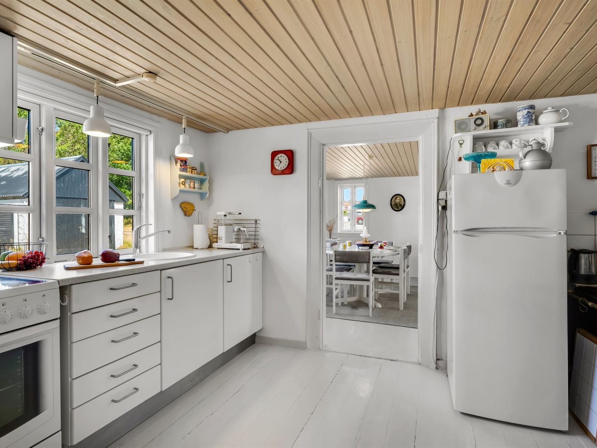 Ett modernt kök med vita skåp, en inbyggd ugn och ett stort kylskåp.