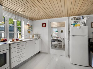 A modern kitchen with white cabinetry, a built-in oven, and a large refrigerator.