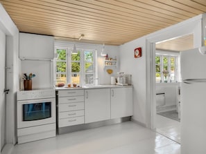 A modern kitchen with white cabinetry, a built-in oven, and a window providing natural light. - "Safir" - 1.7km from the sea by Interhome (Snedsted)