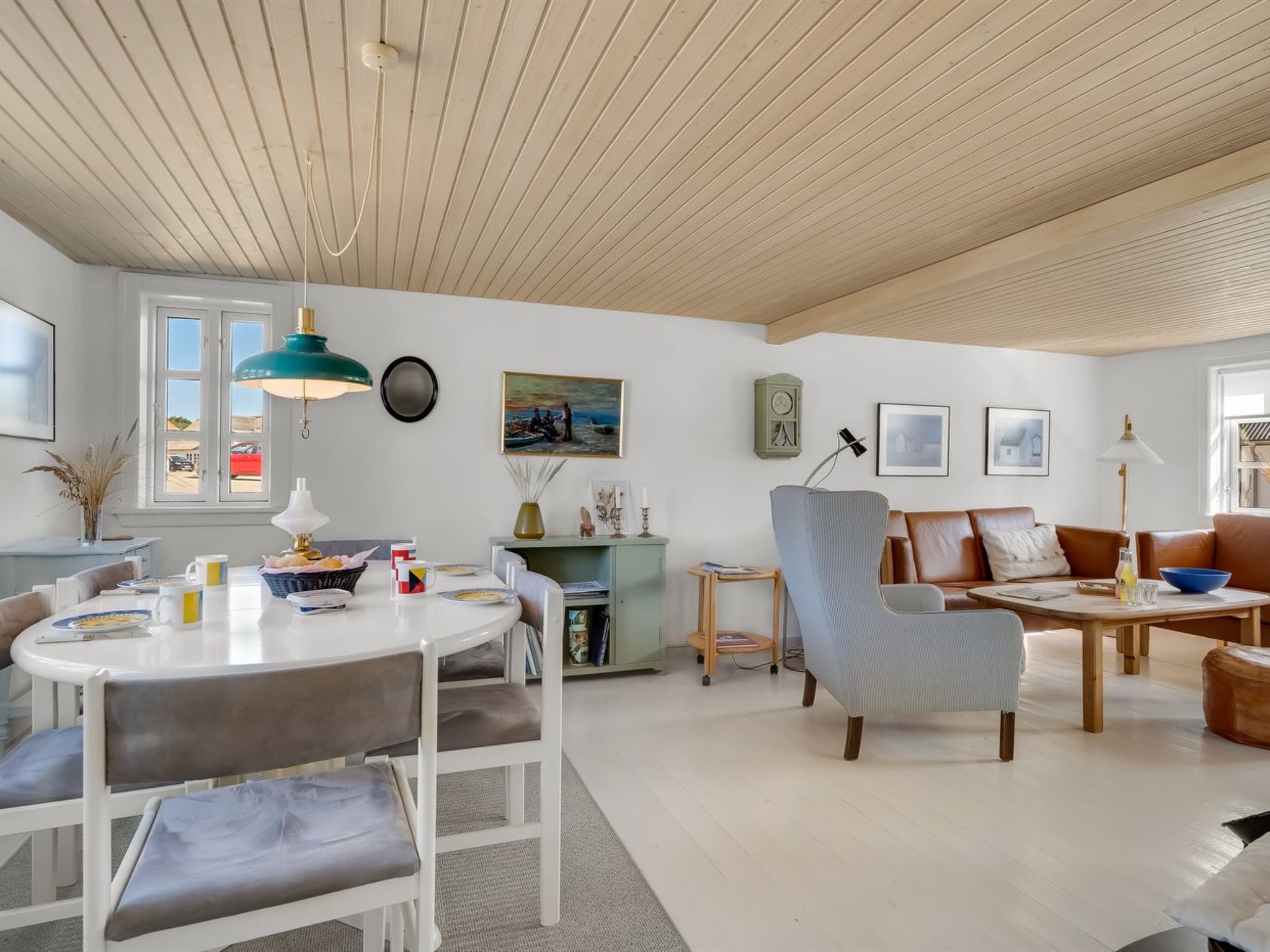 Una sala de estar moderna con comedor, un ventanal grande y un techo con vigas de madera.