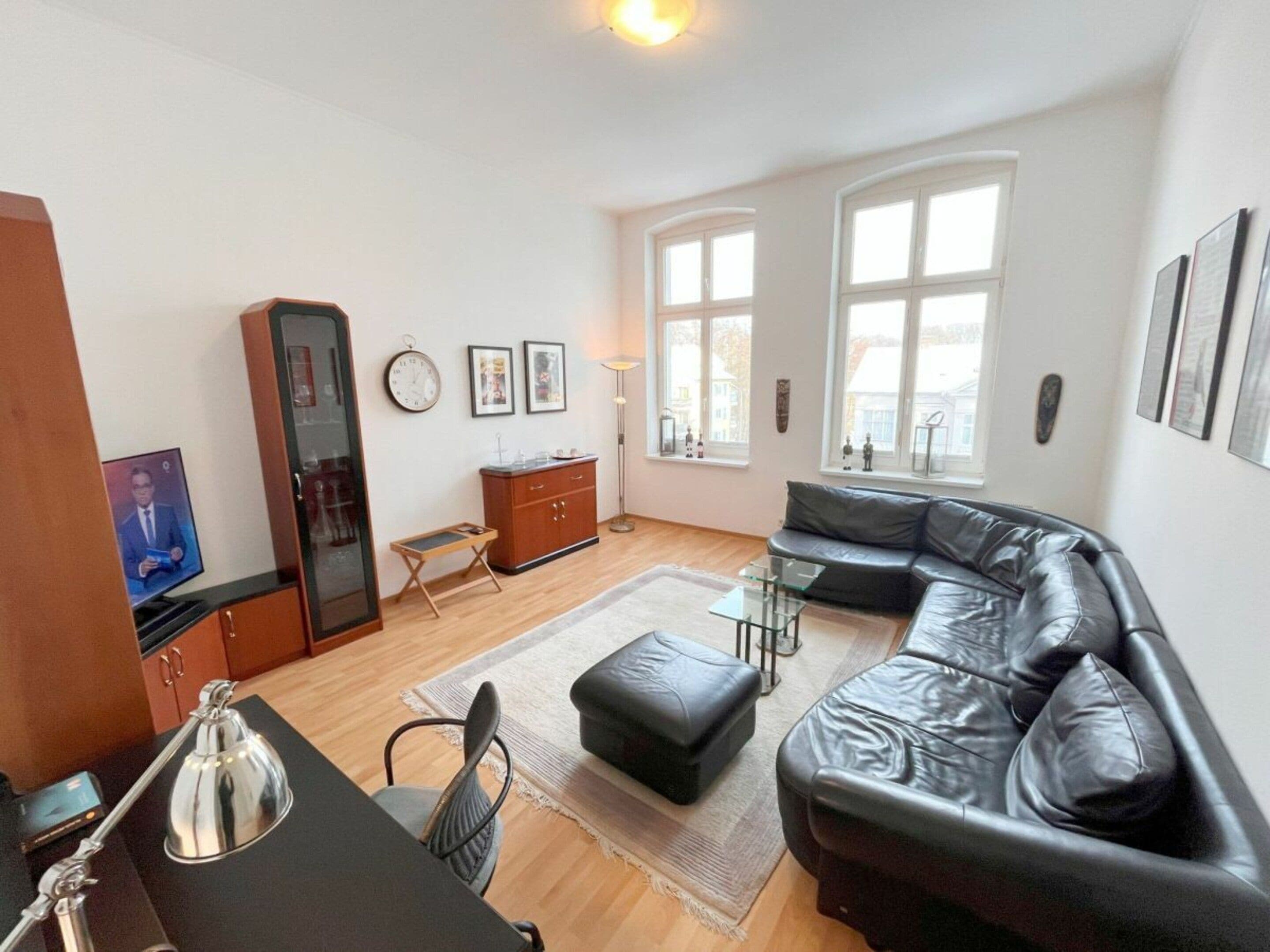 A modern living room with a leather sofa, a small table, a cabinet, and a television.
