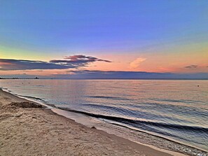 Ein Strand mit ruhigem Meer und blauem Himmel.