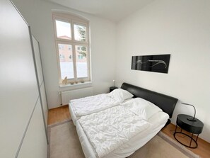 Ein Schlafzimmer mit einem Bett, einem Fenster, einer Heizung und einem Wandbild.