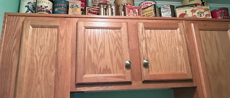 A wooden cabinet with multiple vintage food canisters on top.