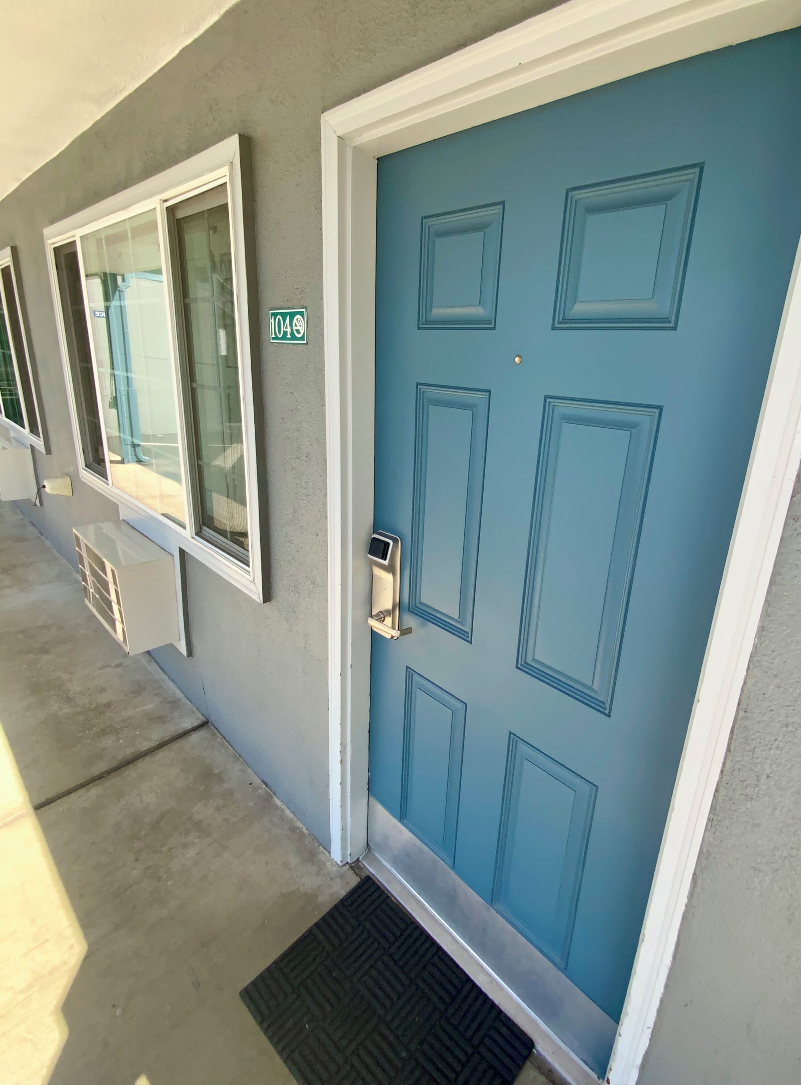 A blue door with a keypad lock, a window with a view of a pool, and a number '404' sign on the wall.