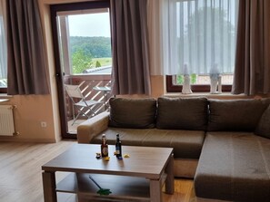 Ein Wohnzimmer mit einer Couch, einem Couchtisch und Blick auf einen Balkon.