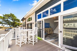 A coastal property with a deck, outdoor seating, and a staircase leading to a covered area. - Coastal Haven at 129th | Ocean View Beach Retreat! (Ocean City)