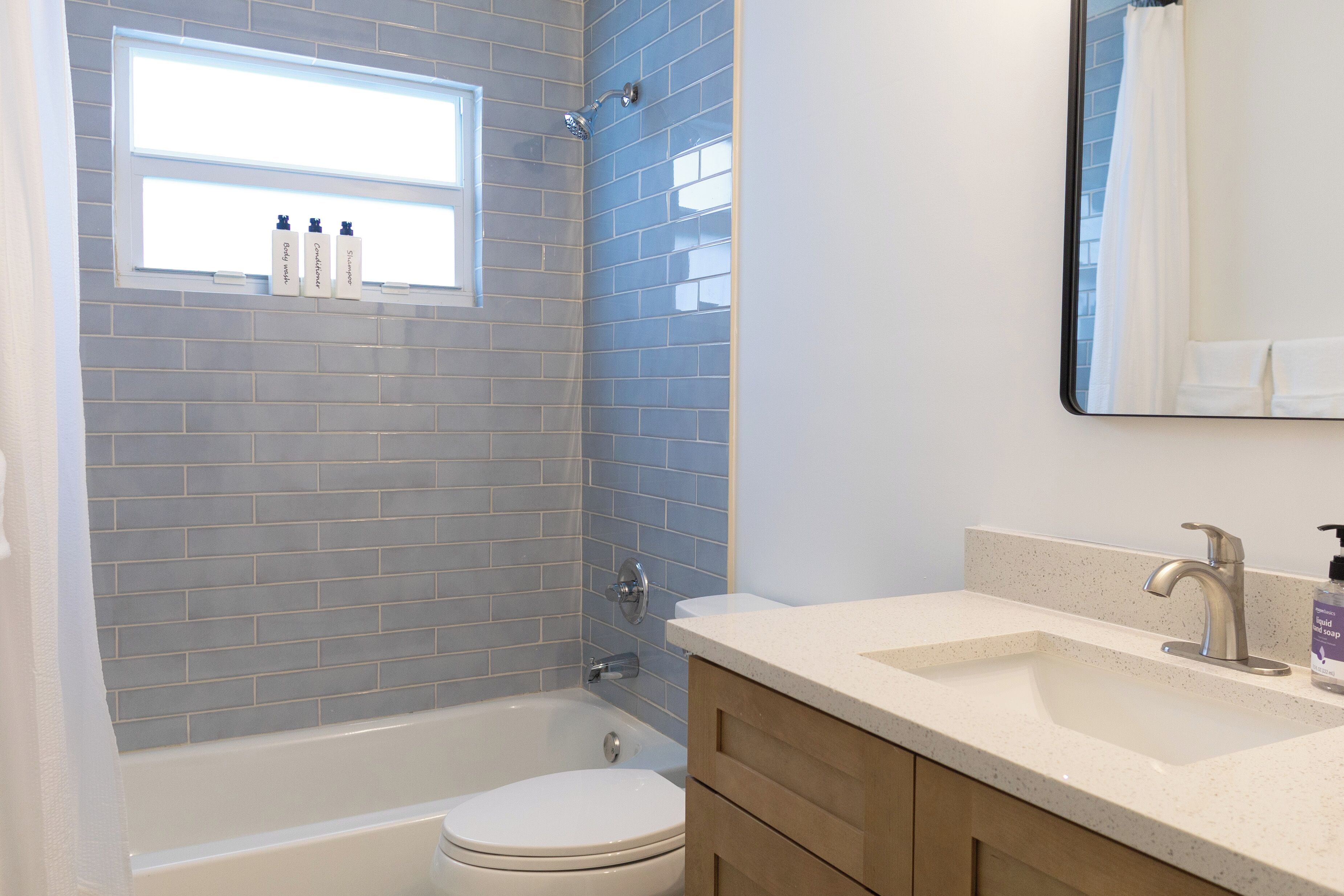 A bathroom with a bathtub, toilet, vanity, and a window above the sink.
