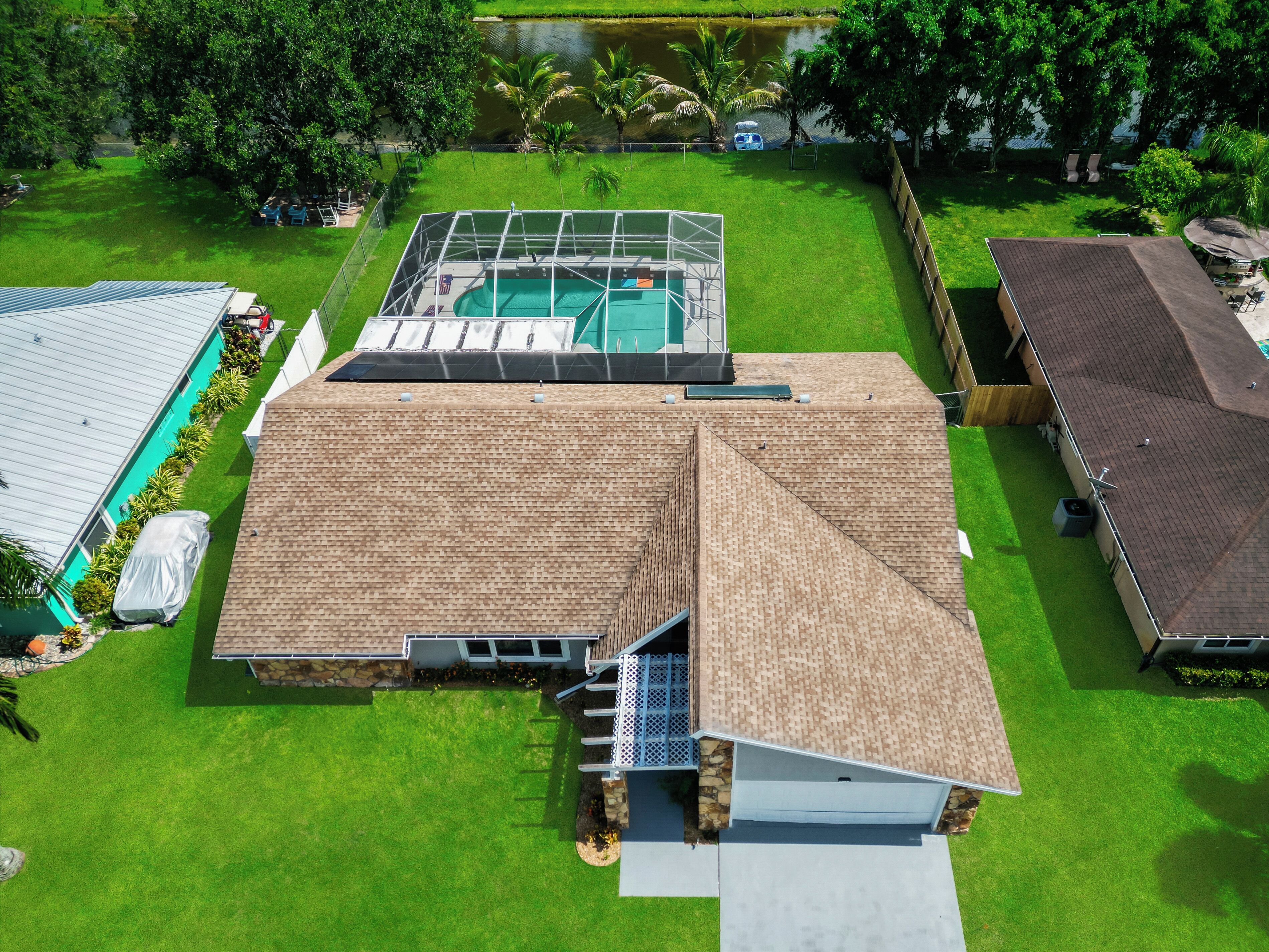 A residential property with a swimming pool, a covered patio, and a well-maintained lawn.