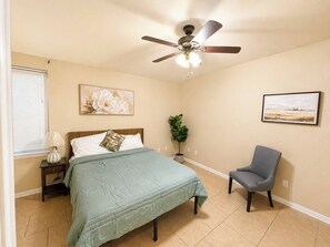 A bedroom with a bed, a chair, a ceiling fan, and a window with blinds. - 3BR Near Fort Cavazos | TDY • PCS • Extended Stay (Killeen)
