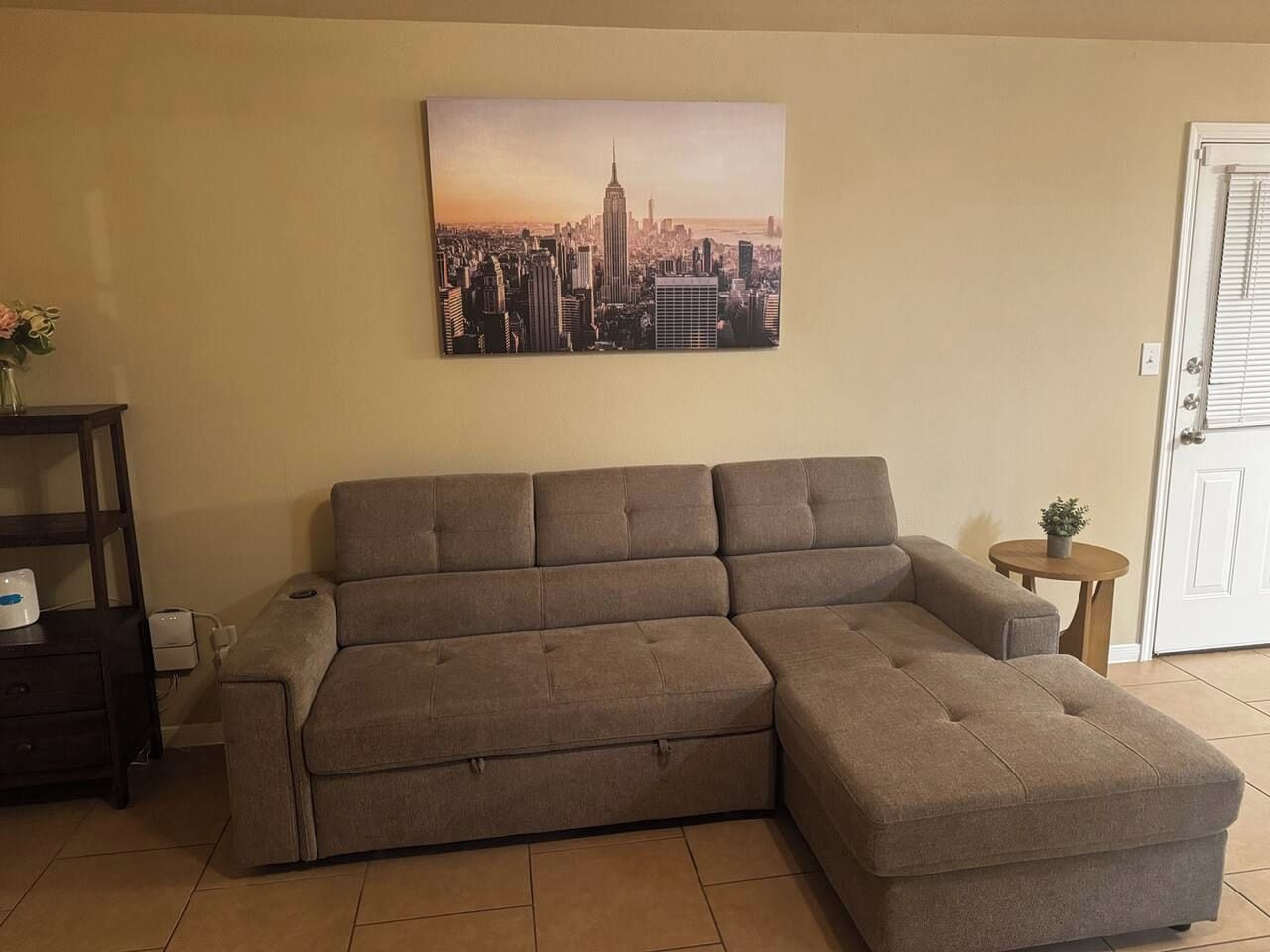 A sectional sofa in a living room with a cityscape painting above it.