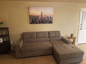 A sectional sofa in a living room with a cityscape painting above it. - 3BR Near Fort Cavazos | TDY • PCS • Extended Stay (Killeen)