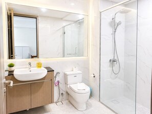 Et moderne badeværelse med en hvid vask, toilet og brusekabine med glasvægge.