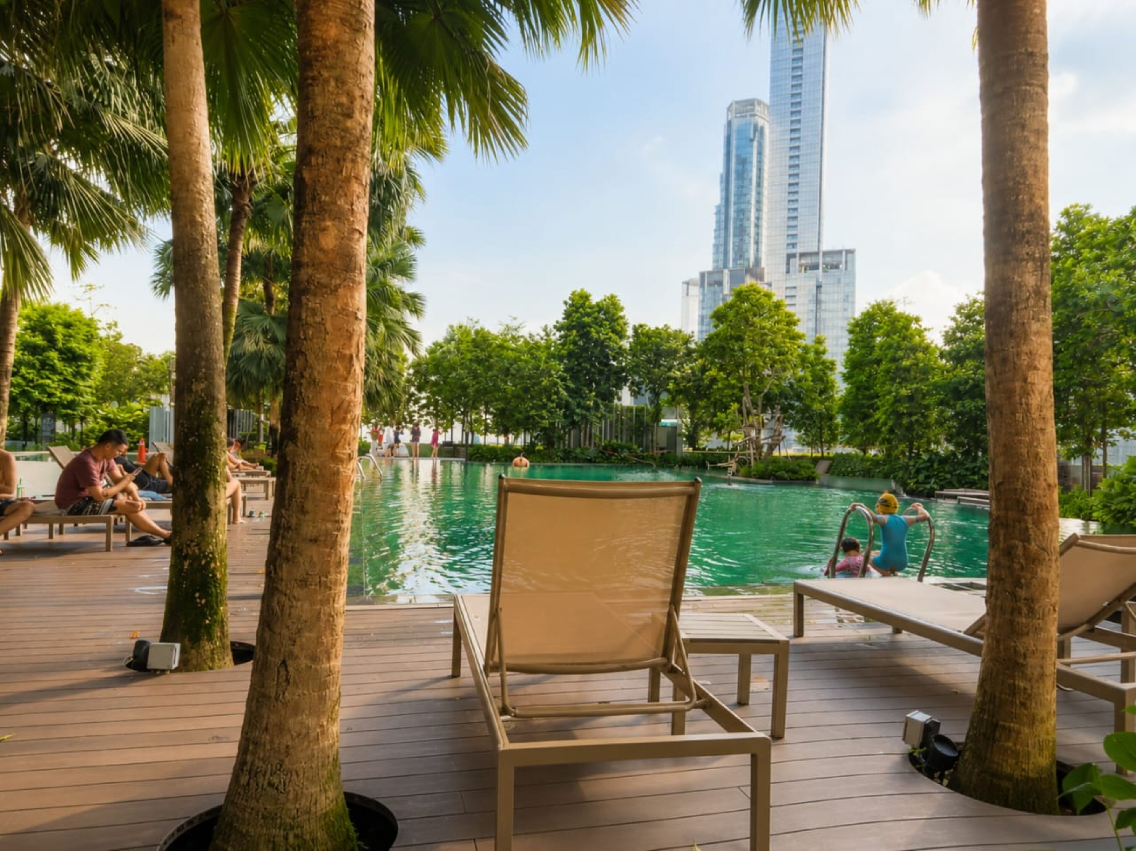 Área de piscina com espreguiçadeiras e vista para o horizonte urbano.