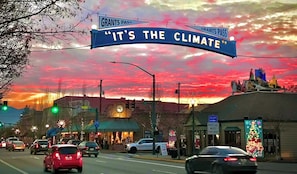 Escena callejera con un letrero destacado que dice 'IT'S THE CLIMATE' y 'GRANTS PASS'.