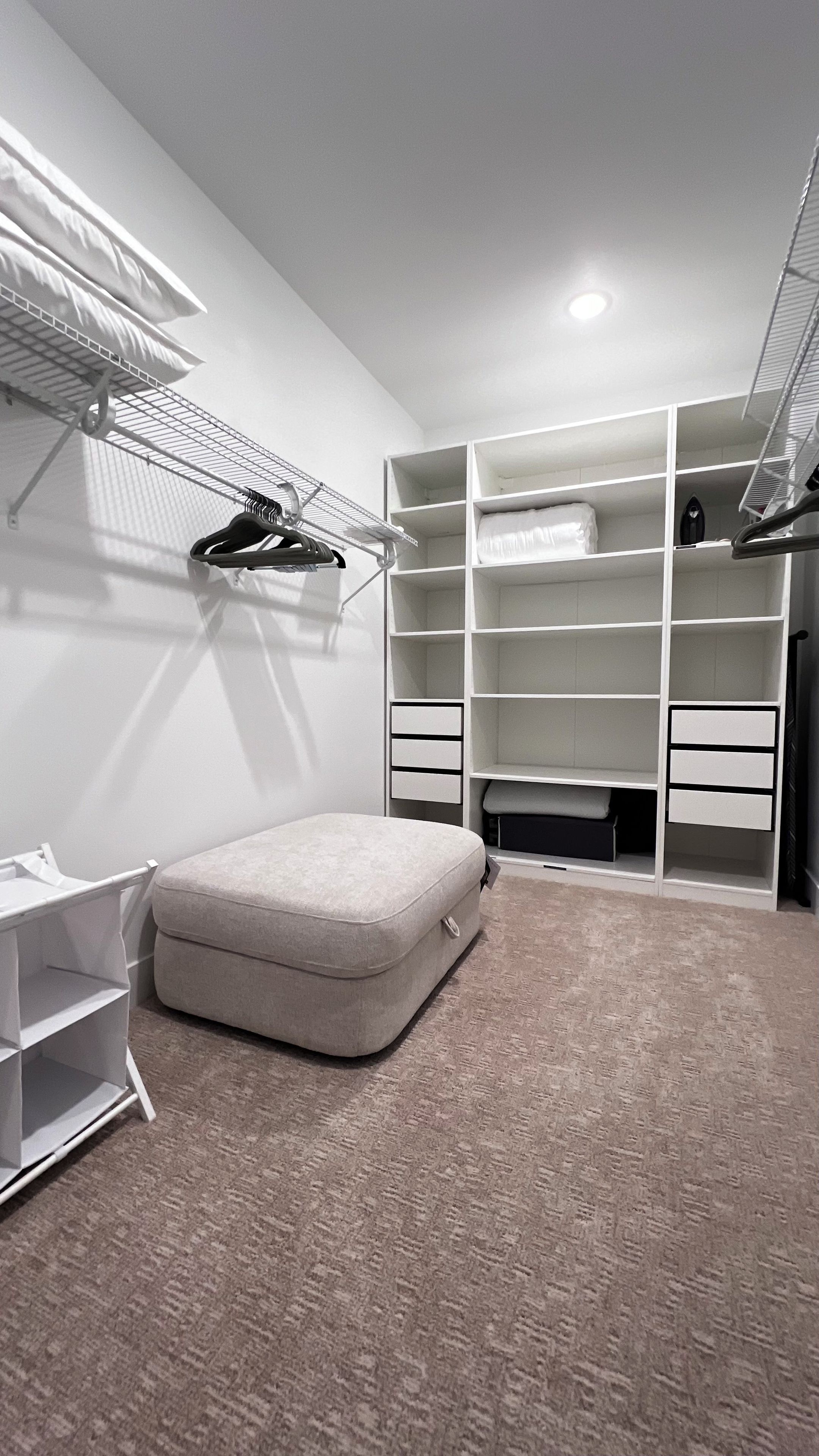 A bedroom with a bed, a bedside table, a wardrobe, and a hanging shoe rack.