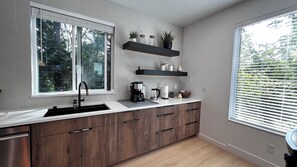 A modern kitchen with a large window, built-in shelves, and a wooden countertop. - Modern Bremerton Escape Near Ferry & Seattle (Bremerton)