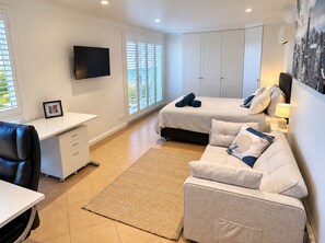 A bedroom with a bed, a desk, a chair, and a TV. - Carinya Coastal Escapes | Bay Views & Bouddi (Daleys Point)