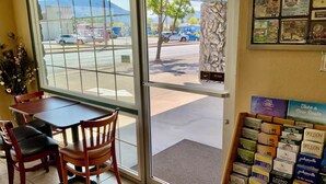 L’intérieur d’un restaurant, avec une table et des chaises, un présentoir rempli de brochures de voyage et une vue sur la rue.