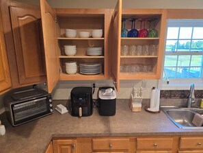 A kitchen with wooden cabinets, a toaster oven, a coffee maker, and a window with a view of a yard.