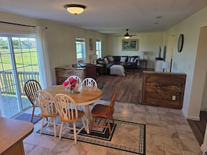 A spacious living area with a dining table, chairs, a sofa, and a kitchen area.
