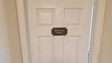 Une porte blanche avec une plaque indiquant « Salle Saratoga » et un trou de serrure.